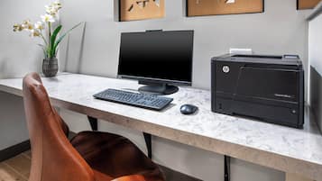A modern office desk with a desktop computer, a printer, and a vase with flowers.