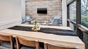 Un comedor moderno con una mesa de madera, sillas y un televisor montado en una pared de madera.