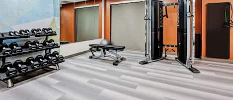 A gym with weightlifting equipment, a bench, and dumbbells.