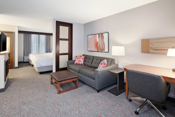 A hotel room with a bed, a sofa, a desk, and a chair.