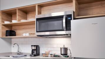 A modern kitchen with a built-in microwave, a coffee maker, and a kettle on the countertop.