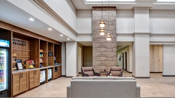 Un vestíbulo moderno con kitchenette, zona de estar y mostrador de recepción.