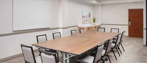 Una sala conferenze con un lungo tavolo, sedie, una lavagna e una porta.