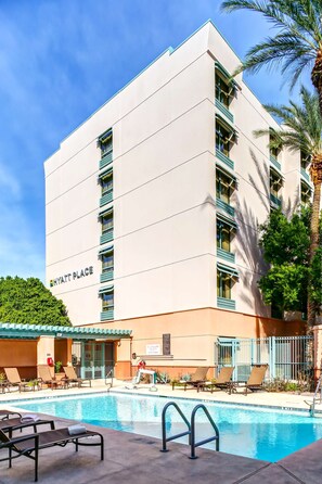 Experience the comfort of a Hyatt Place hotel, featuring a flat roof and symmetrical design, with a swimming pool and lounge chairs.