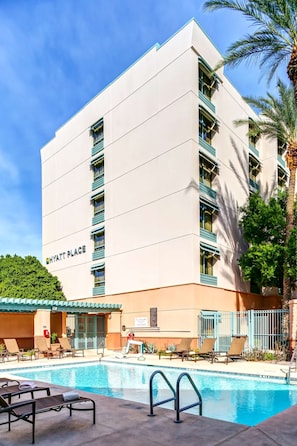 Experience the comfort of a Hyatt Place hotel, featuring a flat roof and symmetrical design, with a swimming pool and lounge chairs.