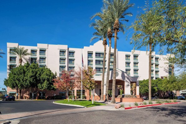 Stunning hotel with a central entrance, palm trees, and a flat roof.