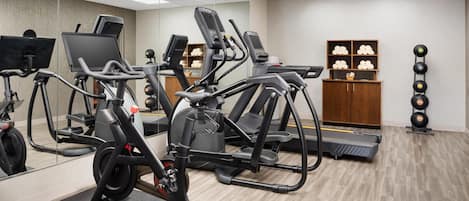 Un gimnasio con equipo de ejercicio, un espejo y un armario de madera con adornos.