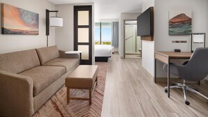Habitación de hotel moderna con sofá, una mesita, escritorio con silla, cama y obras de arte en las paredes.