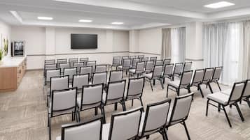 A conference room with rows of chairs, a flat-screen TV, and a plant.