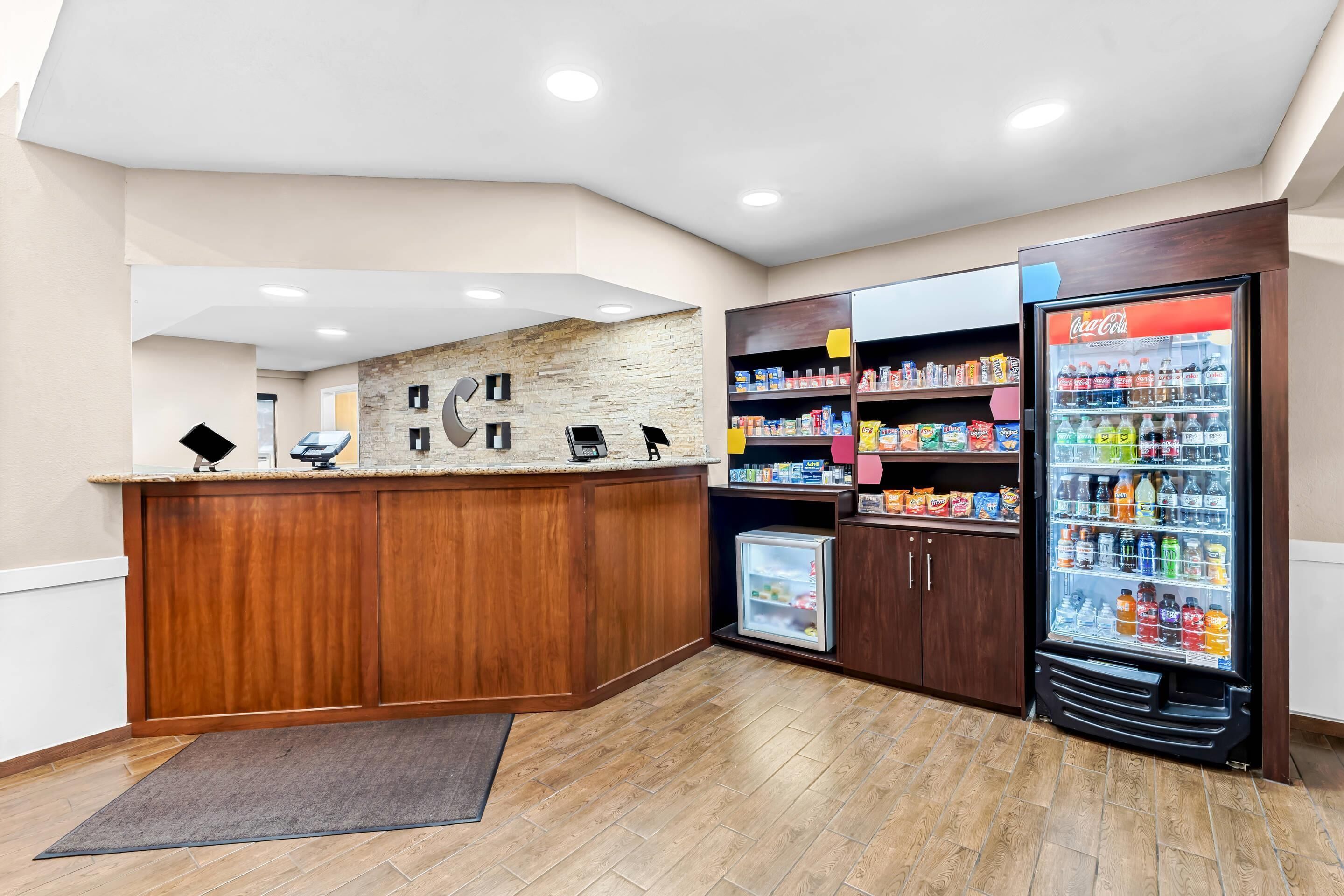 A reception area with a wooden counter, a stone wall, a Coca-Cola refrigerator, and a small cooler.