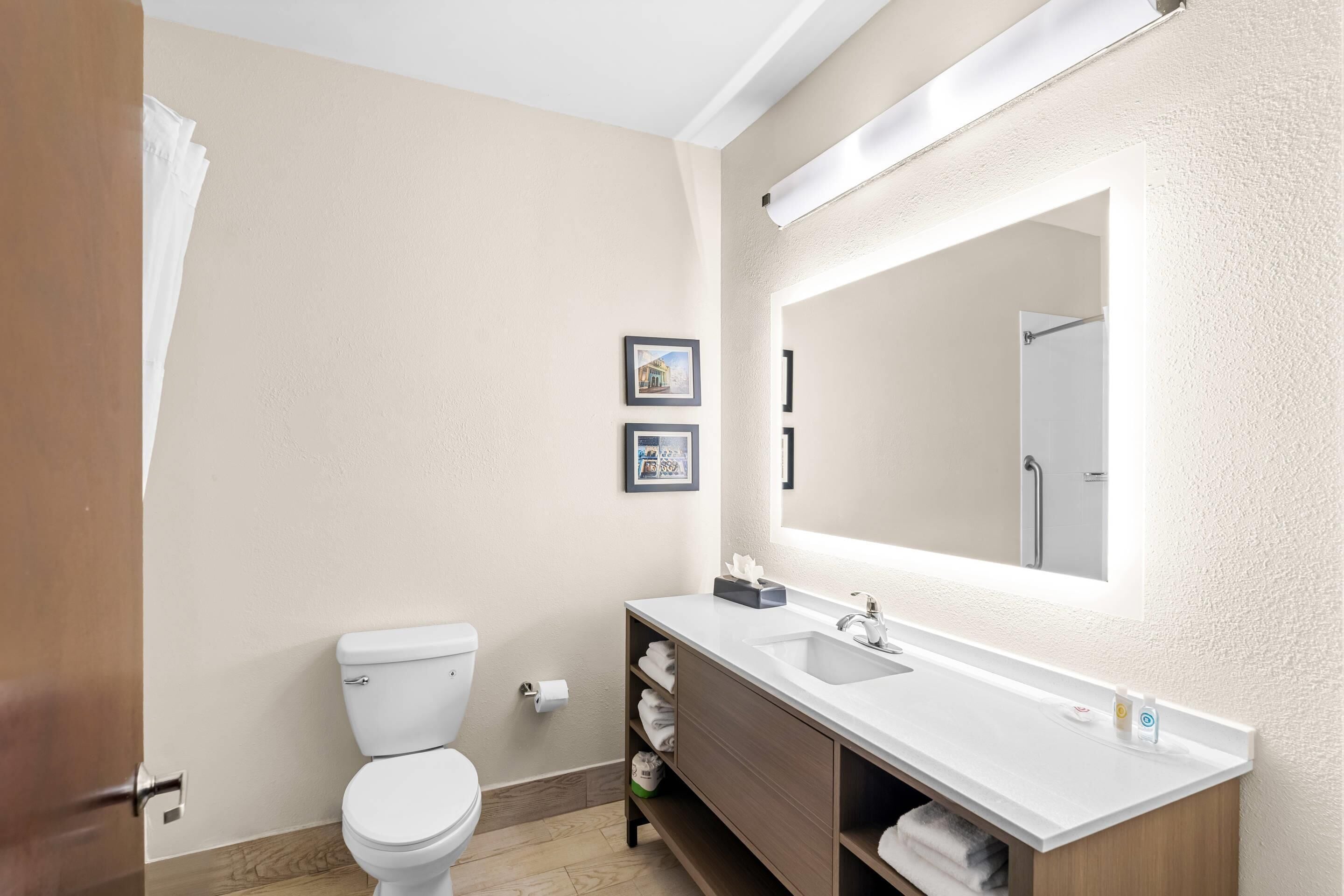 Un baño moderno con inodoro, lavamanos y espejo.