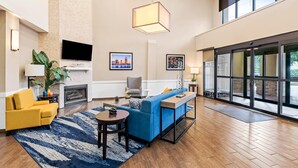 A modern living room with a blue sofa, yellow armchair, and a fireplace. - Comfort Suites Daphne - Mobile East Bay (Daphne)