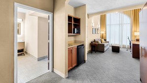 A hotel room with a kitchenette, a sofa, a desk, and a large window with curtains. - Comfort Suites Daphne - Mobile East Bay (Daphne)