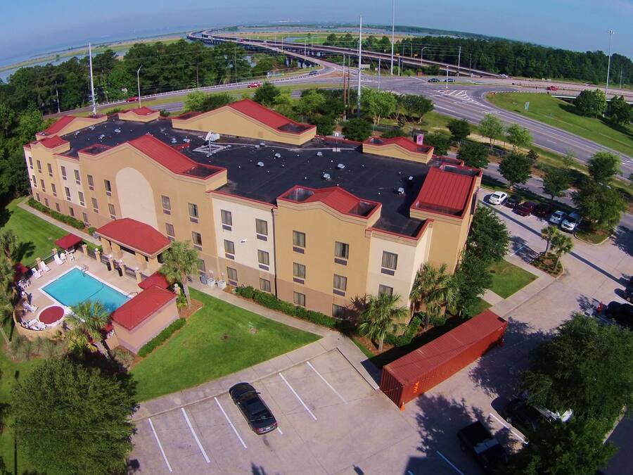 A hotel with a swimming pool, a parking lot, and a view of a highway and bridge.
