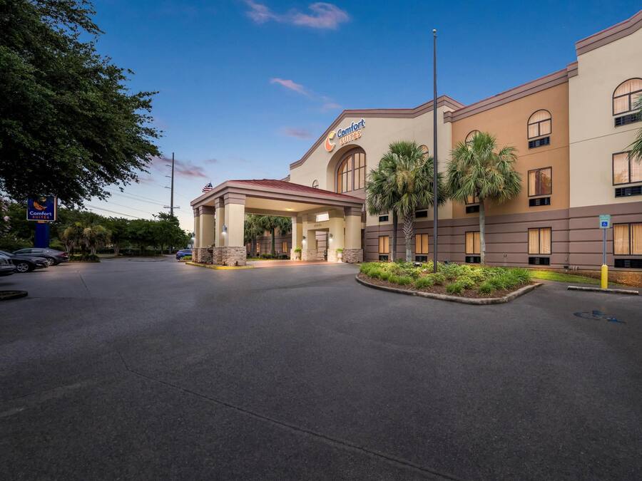 Un hotel Comfort Suites con ingresso coperto, palme e parcheggio.