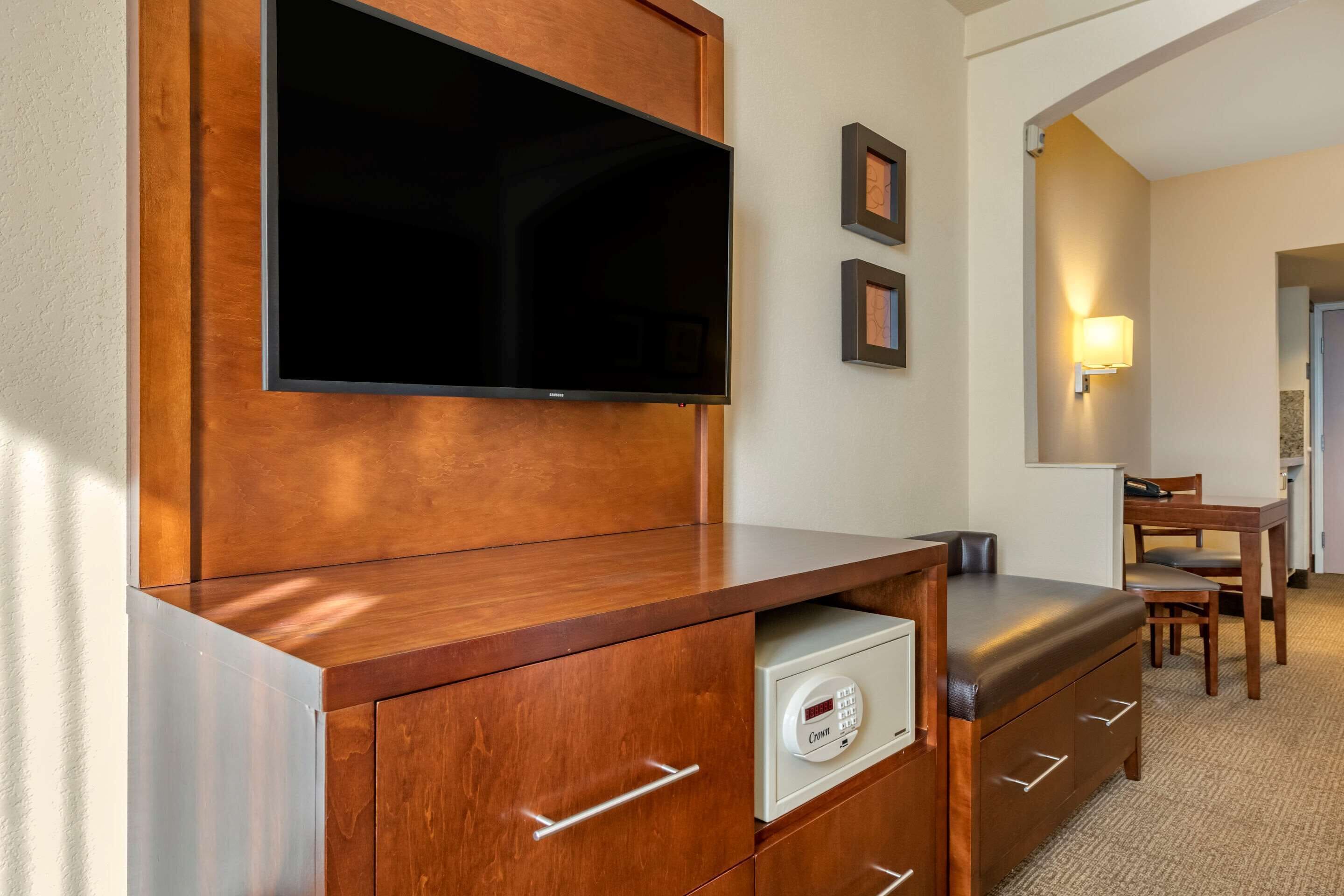 Une chambre d’hôtel équipée d’un meuble en bois, d’un téléviseur à écran plat, d’un coffre-fort, d’un bureau et d’une chaise.
