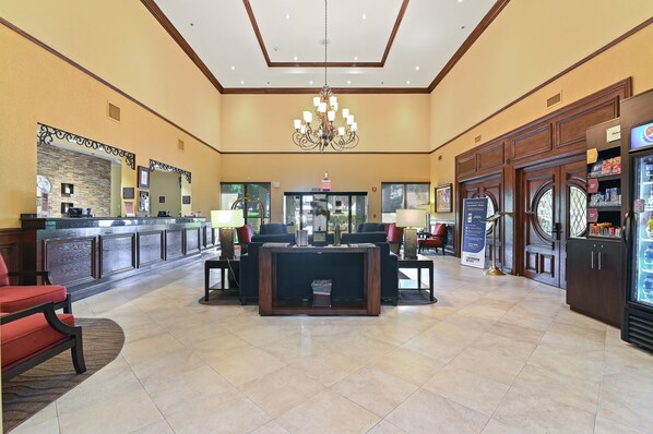 A spacious lobby with a reception desk, seating area, and a refrigerator.
