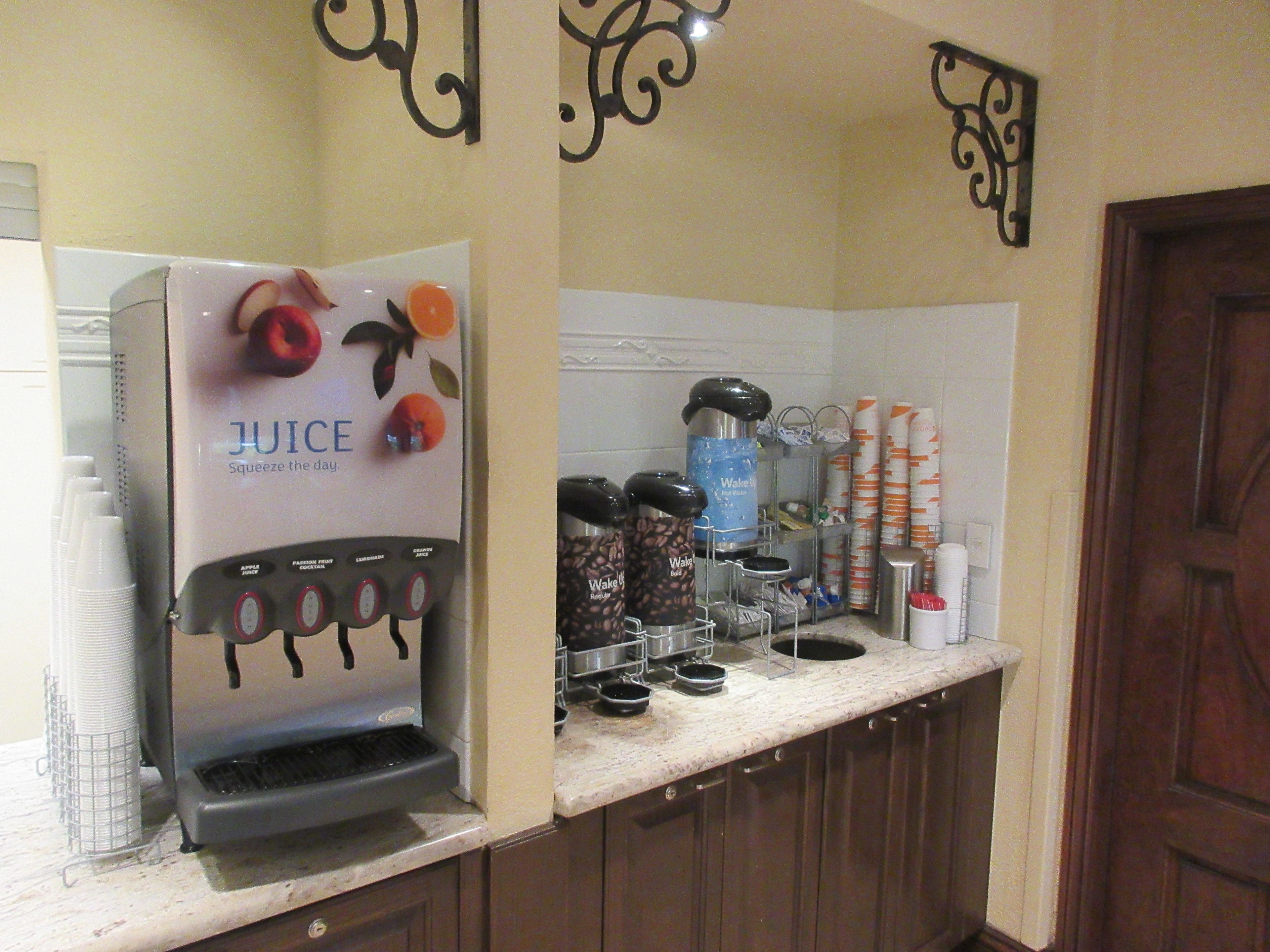 A kitchen area with a juice dispenser, coffee maker, and various kitchen appliances.