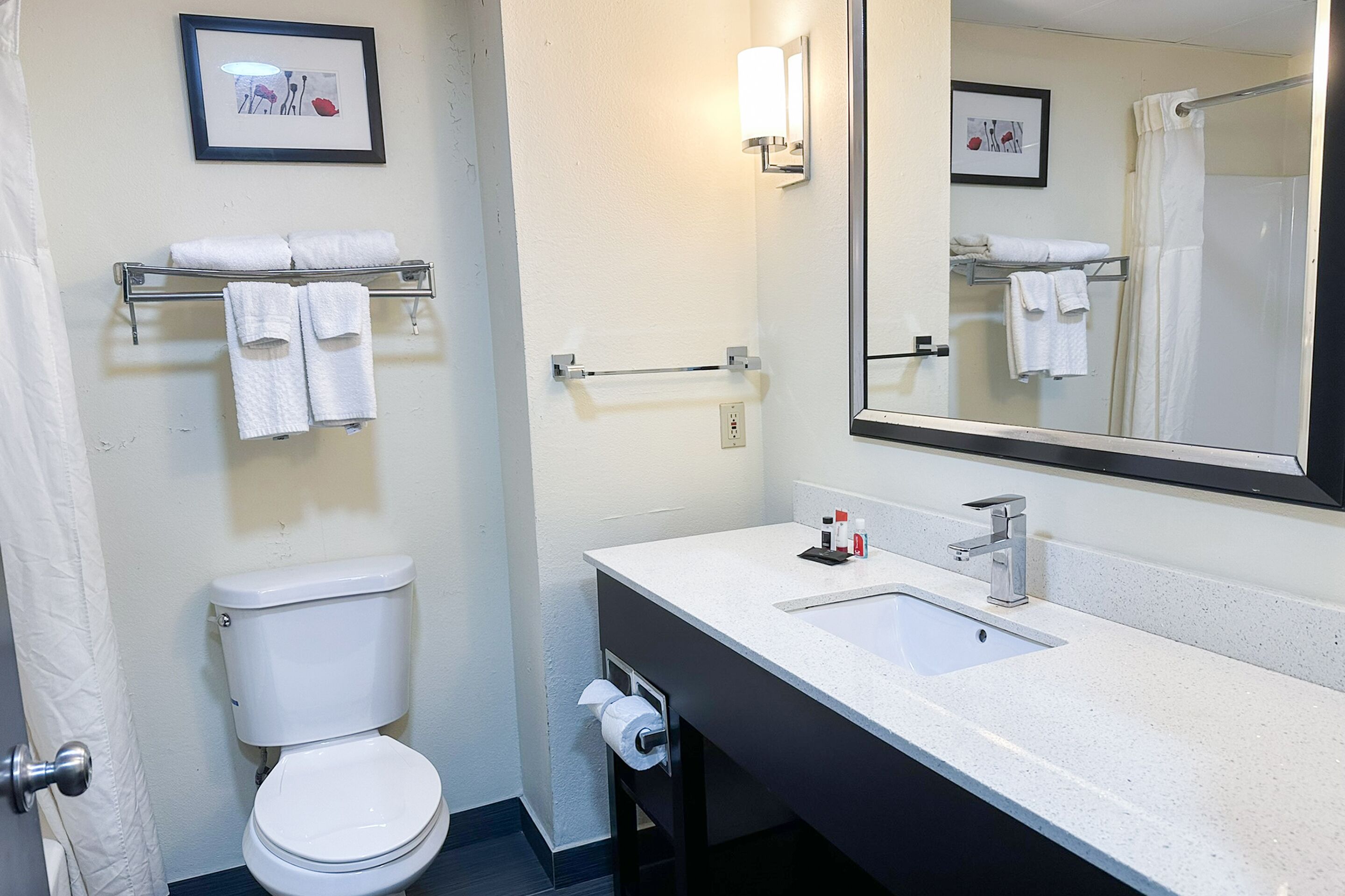 A modern bathroom with a white toilet, a sink with a mirror, and a towel rack with folded towels.