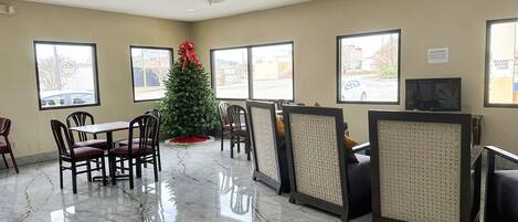 A hotel lobby with a Christmas tree, seating area, and large windows.