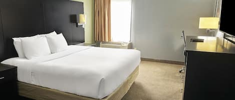 Una habitación de hotel con una cama grande, mesitas de noche, un televisor y un ventanal con cortinas.