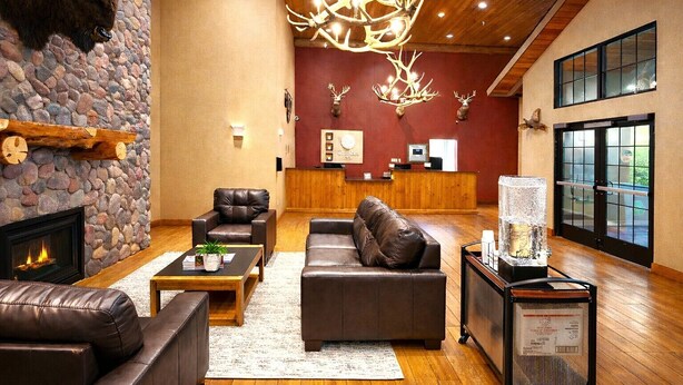 A spacious lobby with a stone fireplace, leather furniture, a chandelier, and a reception desk. - Comfort Inn Owatonna near Medical Center (Owatonna)