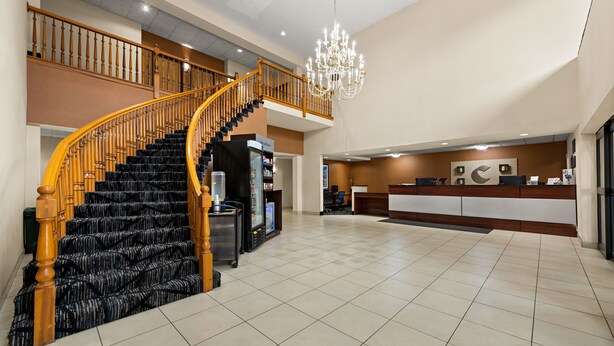 Un vestíbulo amplio con una gran escalera, una mesa de recepción y un candelabro.