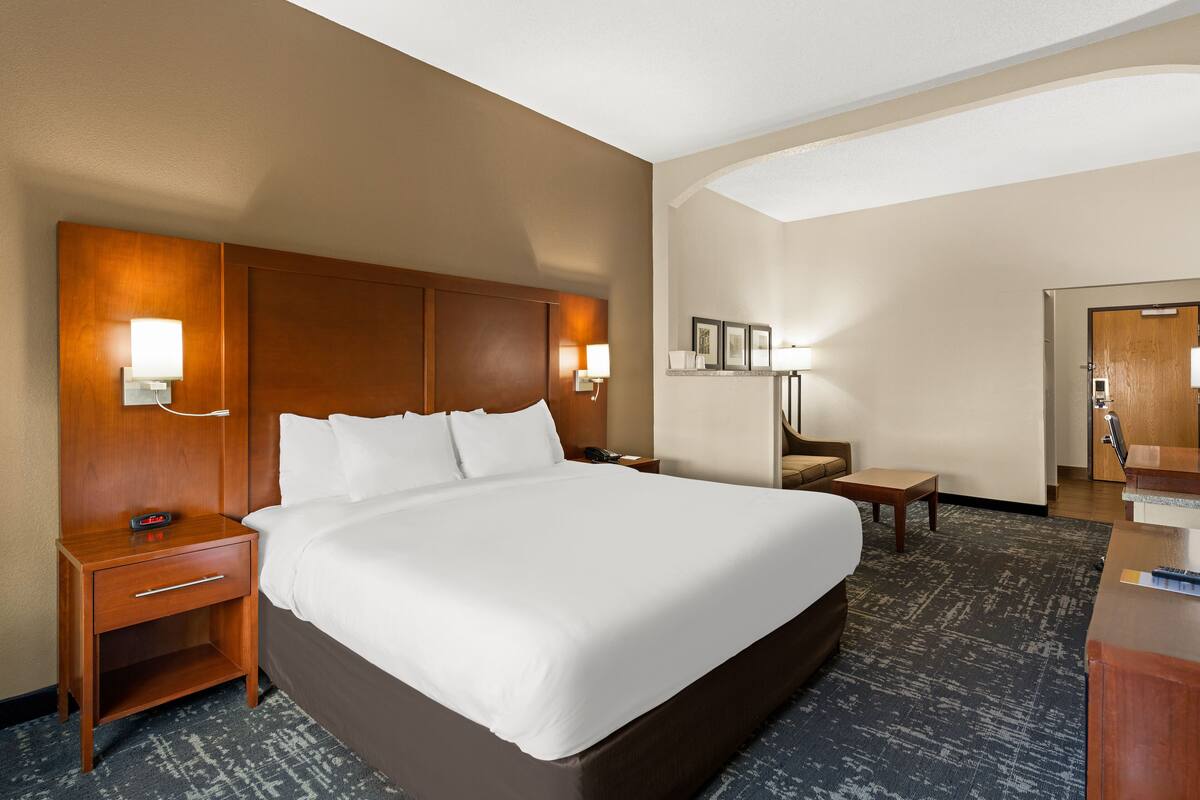 Une chambre d’hôtel avec un grand lit, une table de chevet, un bureau et une chaise.