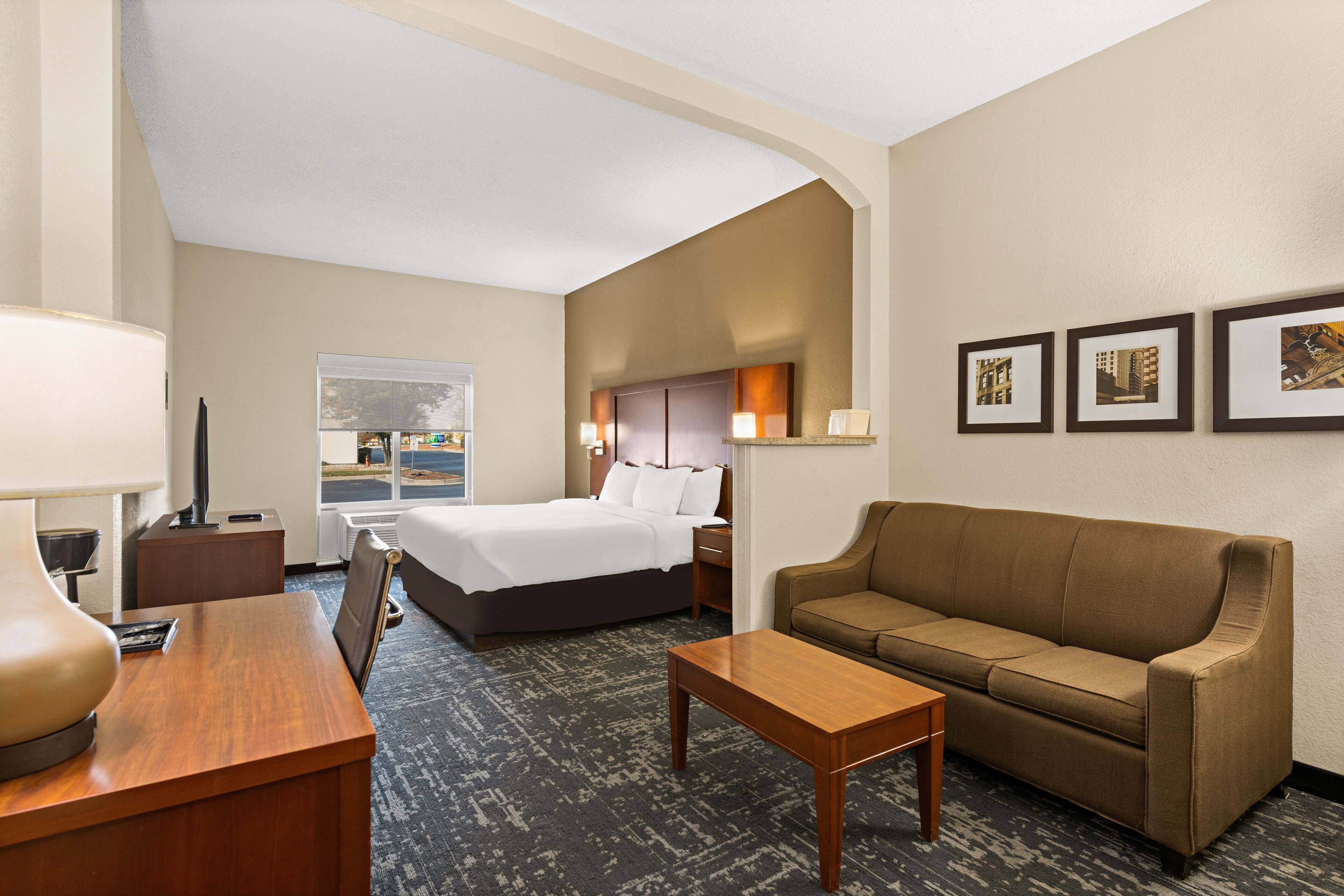 A hotel room with a bed, a sofa, a desk, and a window with a view.