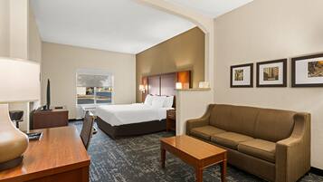 A hotel room with a bed, a sofa, a desk, and a window with a view.