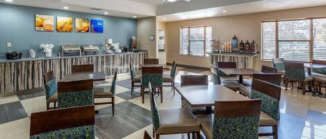 A restaurant with a counter, tables, and chairs.