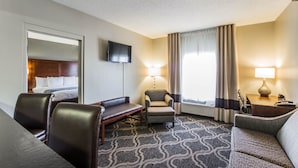 A hotel room with a bed, a desk, a chair, a sofa, and a TV.