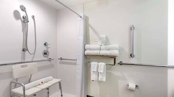 A modern bathroom with a shower, toilet, and a bench.
