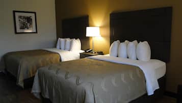 Habitación de hotel con dos camas, una mesita de noche con lámpara, teléfono y un cuadro en la pared.