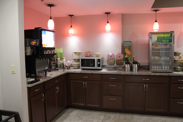 A kitchen with brown cabinets, a microwave, a coffee maker, and a refrigerator.