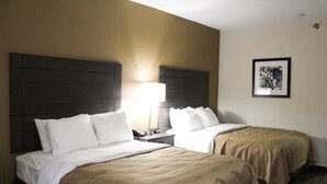 A hotel room with two beds, each with a headboard, a bedside table with a lamp, and a framed picture on the wall. - Quality Inn Clinton - Knoxville North (Clinton)