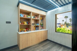 Una kitchenette con armarios de madera y un ventanal con vistas a palmeras y un estacionamiento.