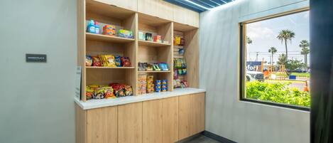 Una kitchenette con armarios de madera y un ventanal con vistas a palmeras y un estacionamiento.