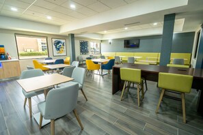 A modern restaurant with a variety of seating options, including booths and tables, and a large window providing a view of the outside.