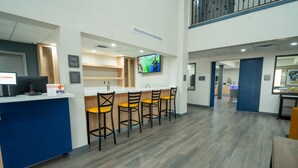 A reception area with a counter, a TV screen, and a bar with stools.