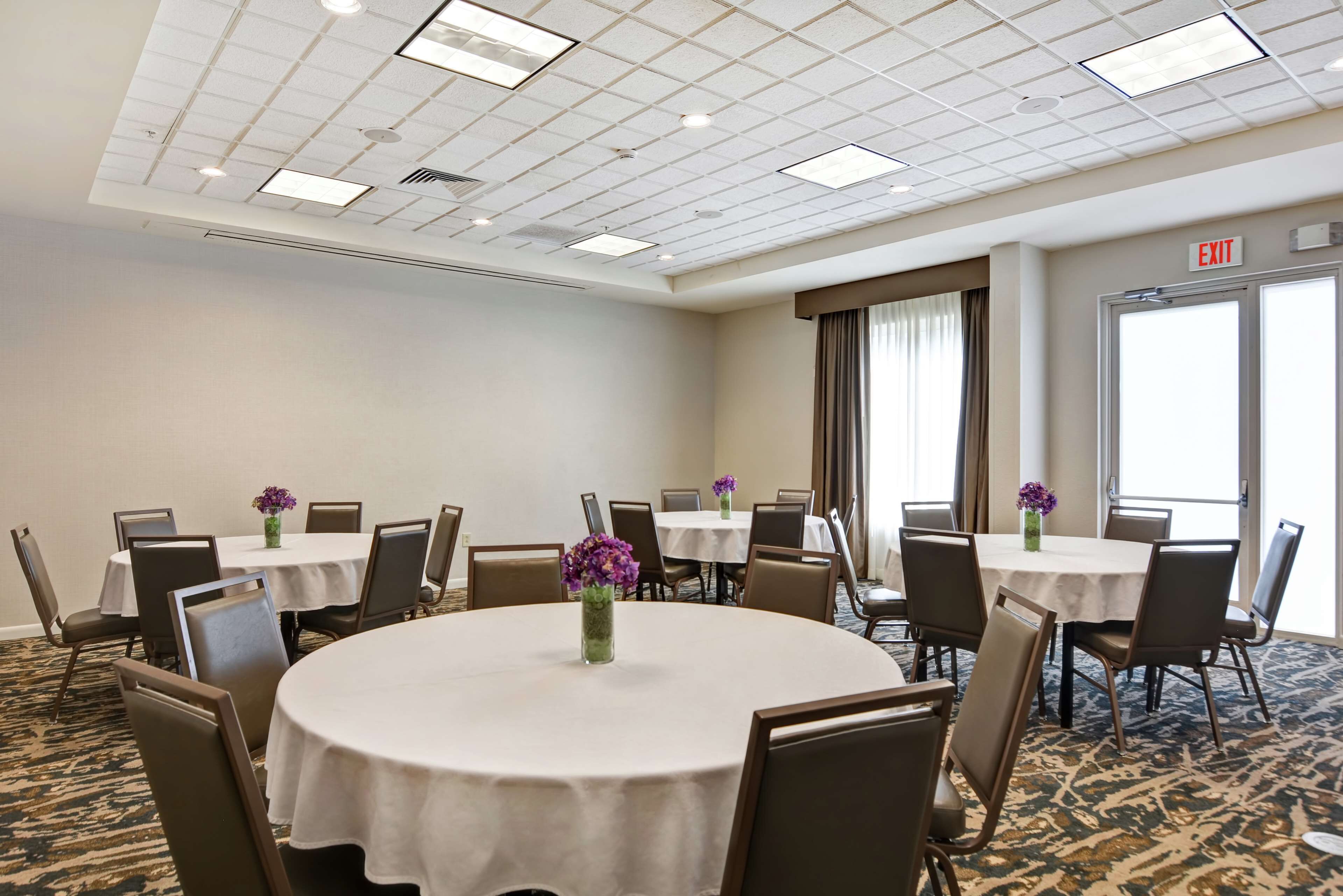 A conference room with round tables, chairs, and floral centerpieces.