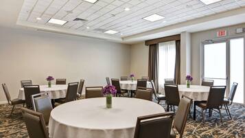 A conference room with round tables, chairs, and floral centerpieces.