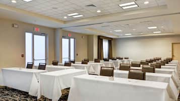 A conference room with multiple tables, chairs, and a carpeted floor.