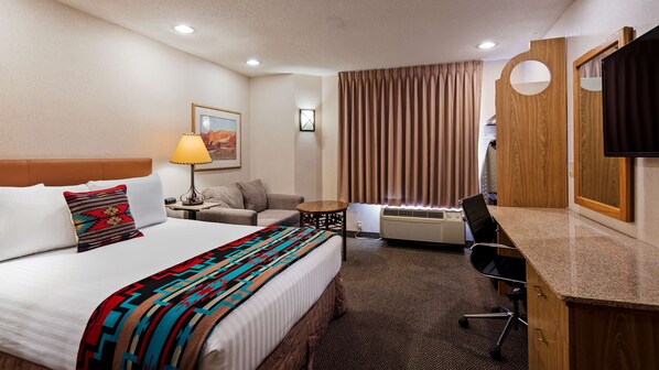 A hotel room with a bed, a desk, a chair, a lamp, a heater, and a television. - Inn at Santa Fe, SureStay Collection by Best Western (Santa Fe)