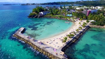 Di pantai, pasir putih, kursi berjemur, dan payung pantai