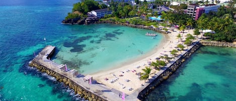 Na praia, areia branca, espreguiçadeiras, guarda-sóis 