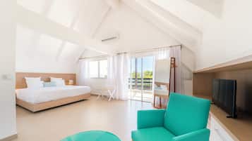 A modern hotel room with a bed, a TV, a seating area, and a balcony with a view.