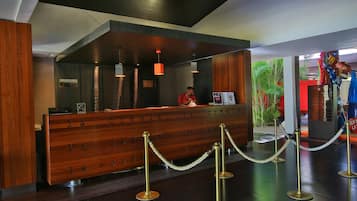 Mostrador de recepción con detalles de madera, una recepcionista y una barrera de cuerda.