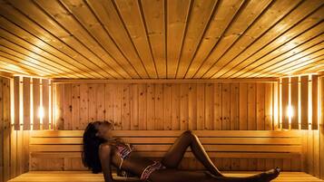 Una sauna de madera con bancos y una persona acostada en uno de ellos.