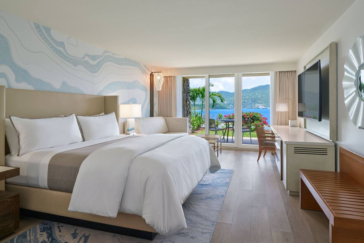 A spacious hotel room with a large bed, a desk, and a television.